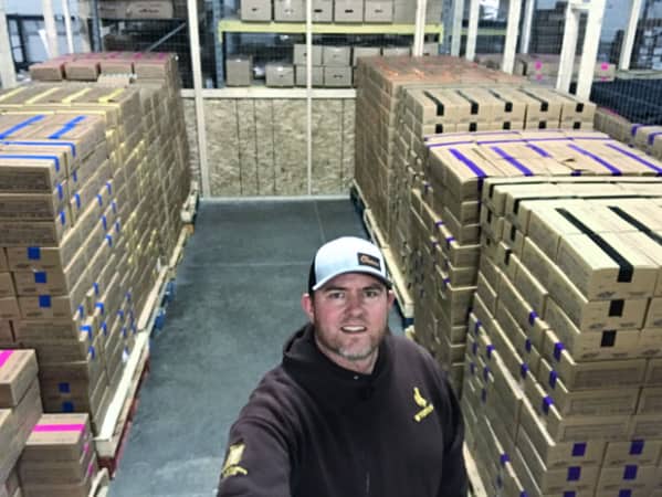 Owner of Success N Fundraising in his storage warehouse surrounded by pallets of boxes with fundraising products.